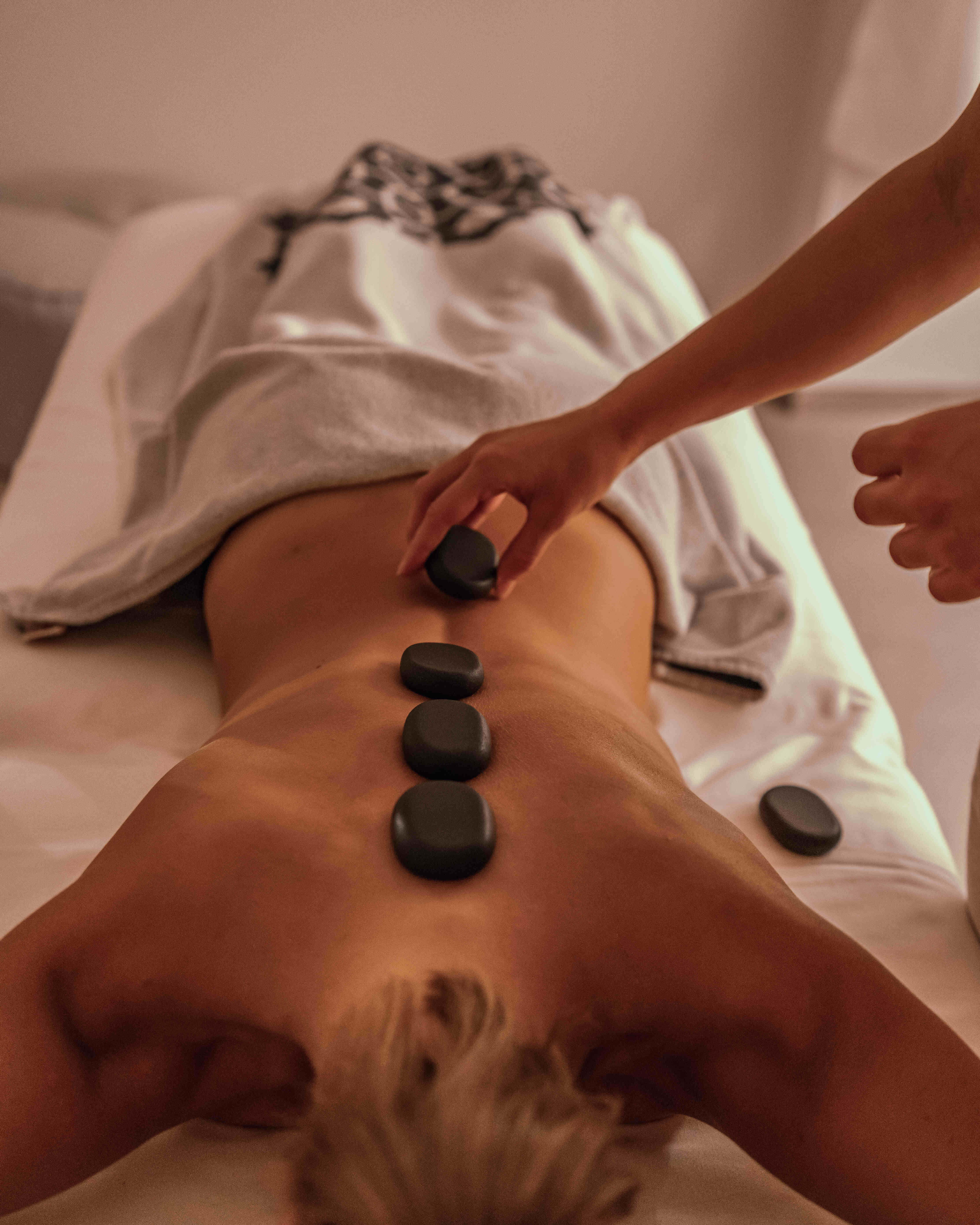 Hot stones are carefully placed on the girl's back for complete relaxation at Harmonia Wellbeing Dukley.